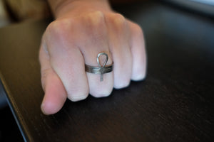 silver ankh ring on finger. hand balled into fist