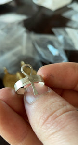 a sterling silver ankh ring held between two fingers