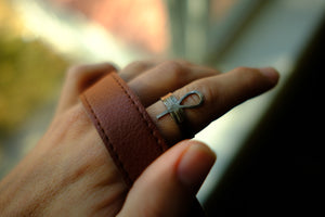 silver ring with ankh design on finger with leather strap 