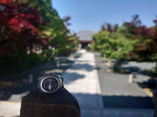 Load image into Gallery viewer, sterling silver japanese kamon family ring in front of a blurred temple
